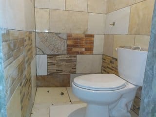 A bathroom with tile walls and floor, toilet in the corner.