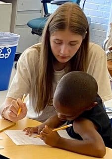 A woman and child are writing on paper.