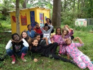 Here's a short alt tag for the image: Kids posing by colorful playhouse outdoors.