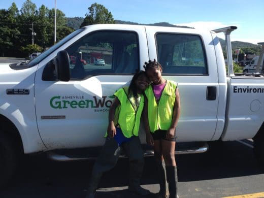 Two girls in safety vests by GreenWorks truck.