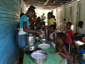 Here's an alt tag for the image: Children receive food at a community meal.