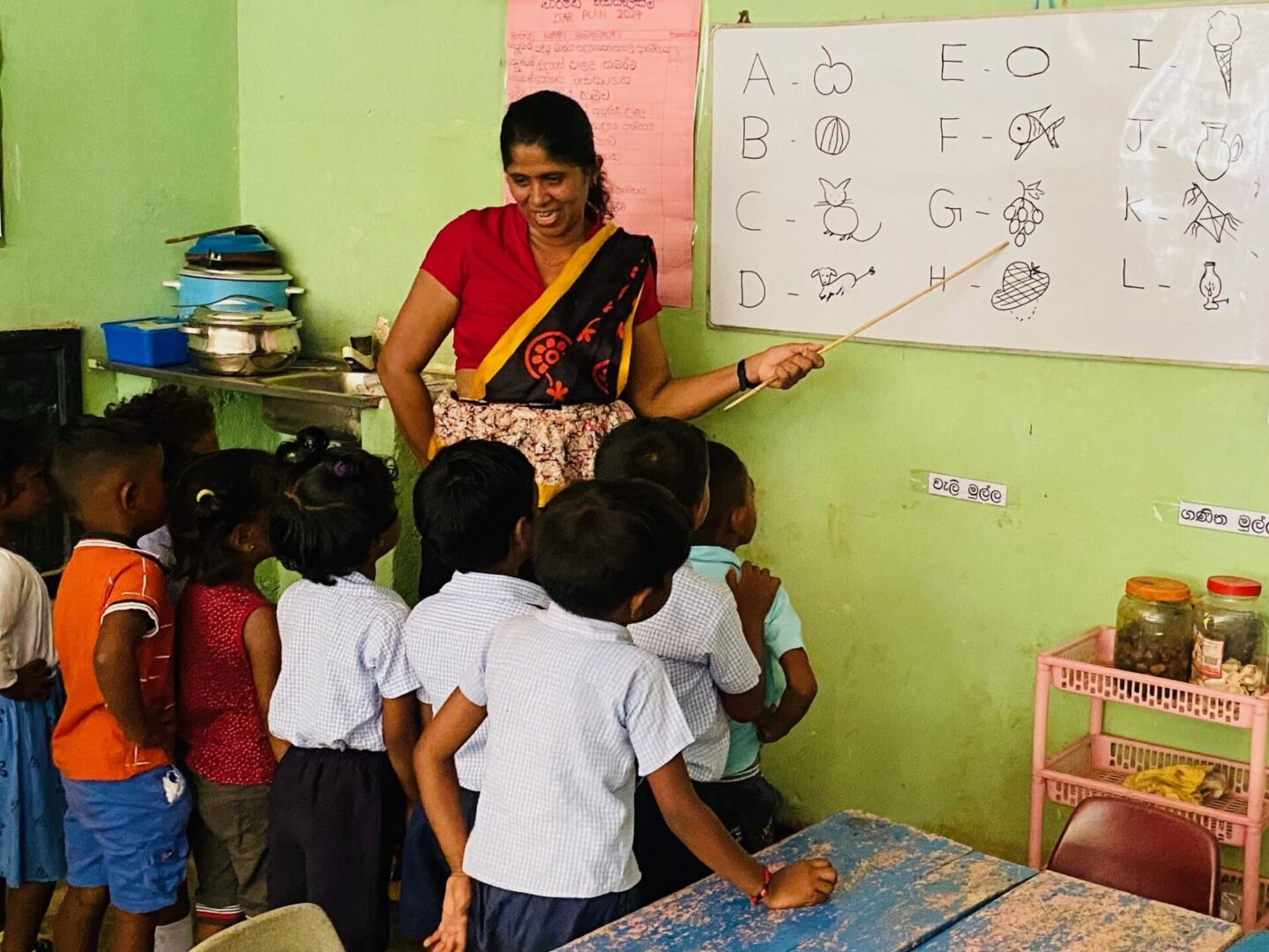 A woman teaching children in front of a whiteboard.