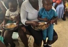 Woman feeding children a meal.
