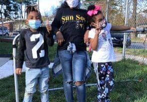 A woman and two children wearing masks posing for the camera.